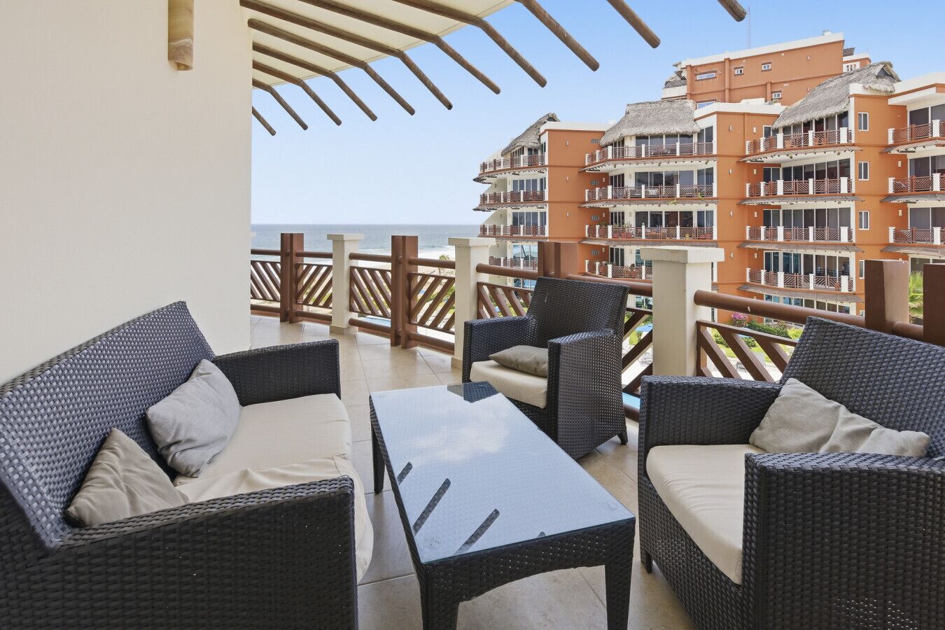 Un balcon doté de meubles en osier et offrant une vue sur un immeuble à plusieurs étages.