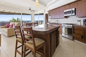 A modern kitchen with a central island, stainless steel appliances, and a view to the outside.