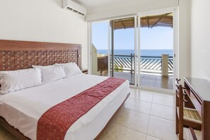 A hotel room with a bed, a desk, and a balcony with a view of the sea. - Beautiful 4 bdm Ocean Front Condo at Vivo Resorts (Bajos de Chila)