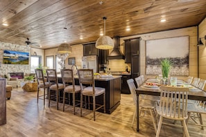 A spacious kitchen with dark cabinets, a central island, and pendant lighting. - Firefly Lodge – Indoor Pool, Theater, Dog Friendly (Sevierville)