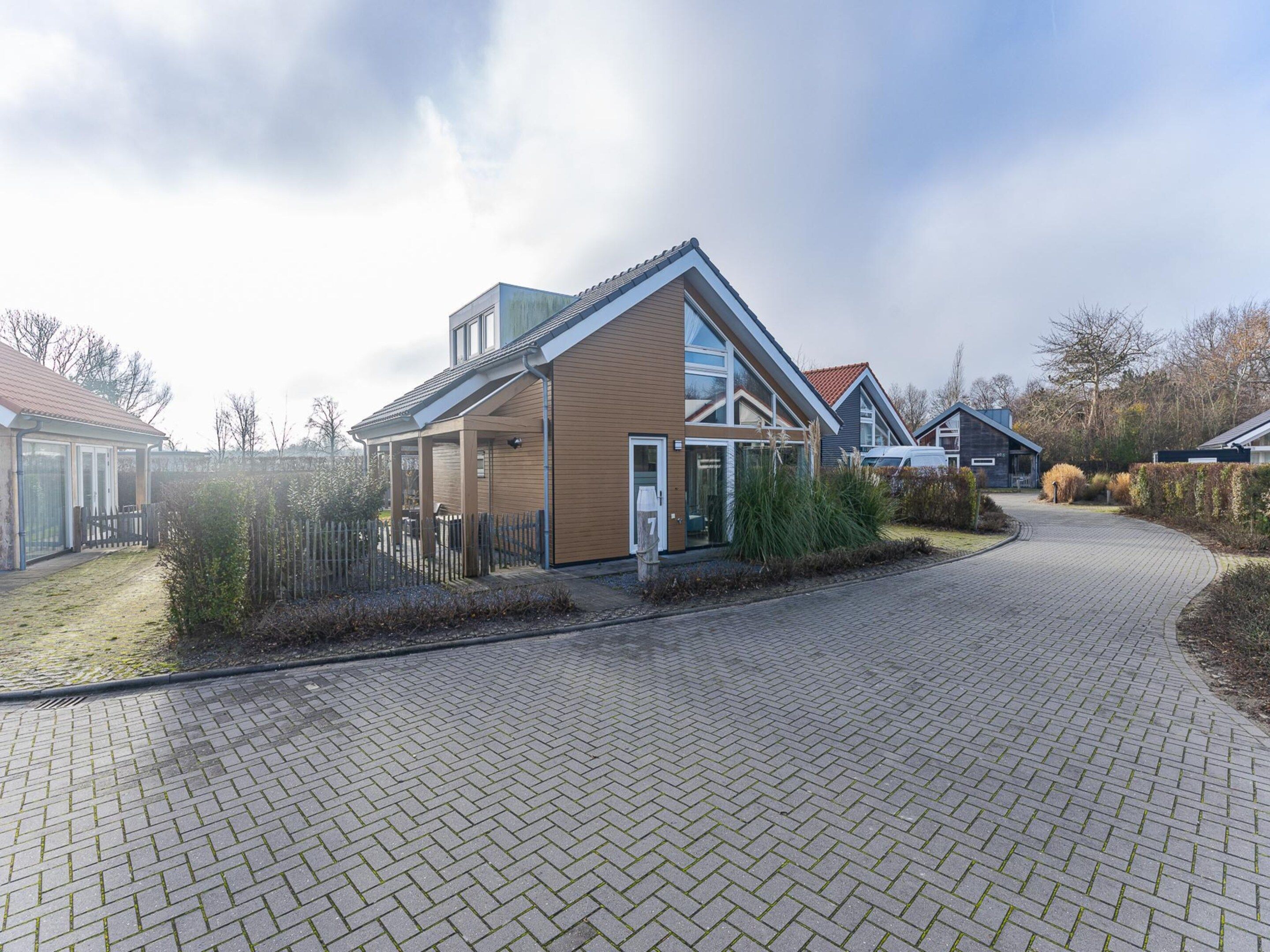 A modern residential area with paved walkways and houses with large windows and sloped roofs.