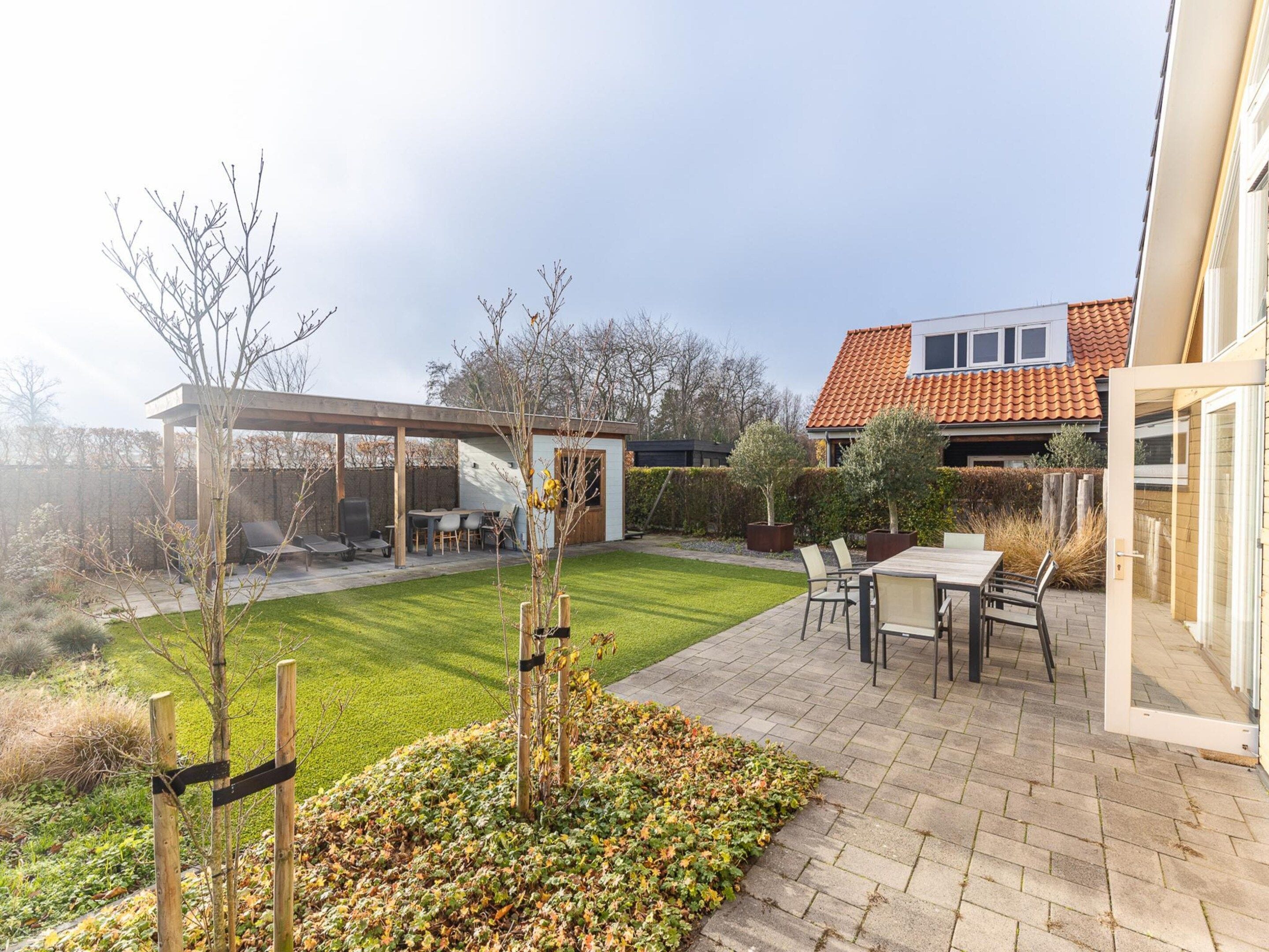 A residential backyard with a patio, outdoor seating, and a well-maintained lawn.
