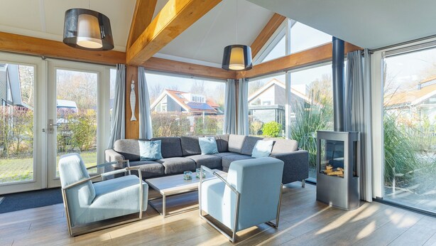 Ein modernes Wohnzimmer mit einer Eckcouch, zwei Sesseln, einem Couchtisch und einem Kamin.