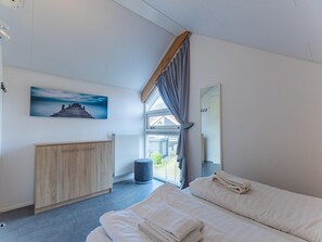 Ein modernes Schlafzimmer mit einem Bett, einem Holzschrank, einer Heizung und einem Fenster mit Vorhängen.