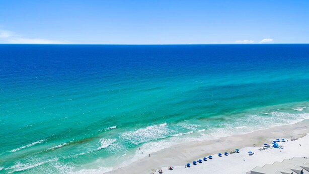 A beach with clear turquoise water, a sandy shore, and blue umbrellas. - YOUR BEST BEACH VACATION EVER  POOL GOLF CART BIKES VERY CLOSE TO BEACH (Santa Rosa Beach)
