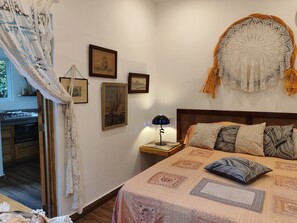 A bedroom with a bed, a nightstand, a lamp, and wall decorations including framed pictures and a tapestry. - Bungalow with a large pool, nestled in a garden with lush, exotic vegetation (Las Terrenas)