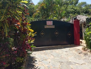A gated entrance with a sign indicating a dog-friendly area. - Bungalow with a large pool, nestled in a garden with lush, exotic vegetation (Las Terrenas)