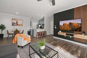 A modern living room with a sofa, a coffee table, and a TV mounted on the wall. - Scottsdale Desert Escape 2BR with Sunrise Peak Views, Pets OK (Scottsdale)