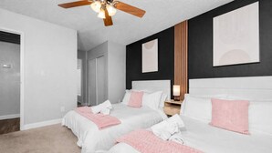 Une chambre d’hôtel avec deux lits, un ventilateur de plafond et une table de chevet avec une lampe.