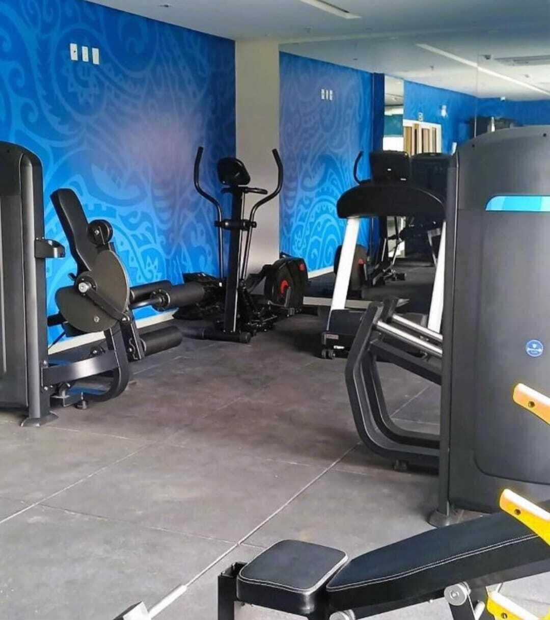 A gym with various exercise equipment, including treadmills, elliptical machines, and weight machines.