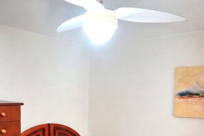 Ein Deckenventilator in einem Raum mit einem hölzernen Schminktisch und einem Gemälde an der Wand.
