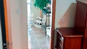 Una habitación con un armario de madera, una planta en maceta y suelo de baldosas.
