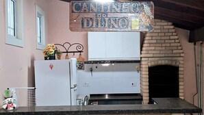Una cocina con horno de ladrillo, armarios blancos y un letrero que dice "Cantinho do Dilio".