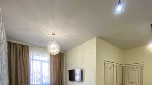 A living room with a sofa, a TV, a ceiling light, and a door.