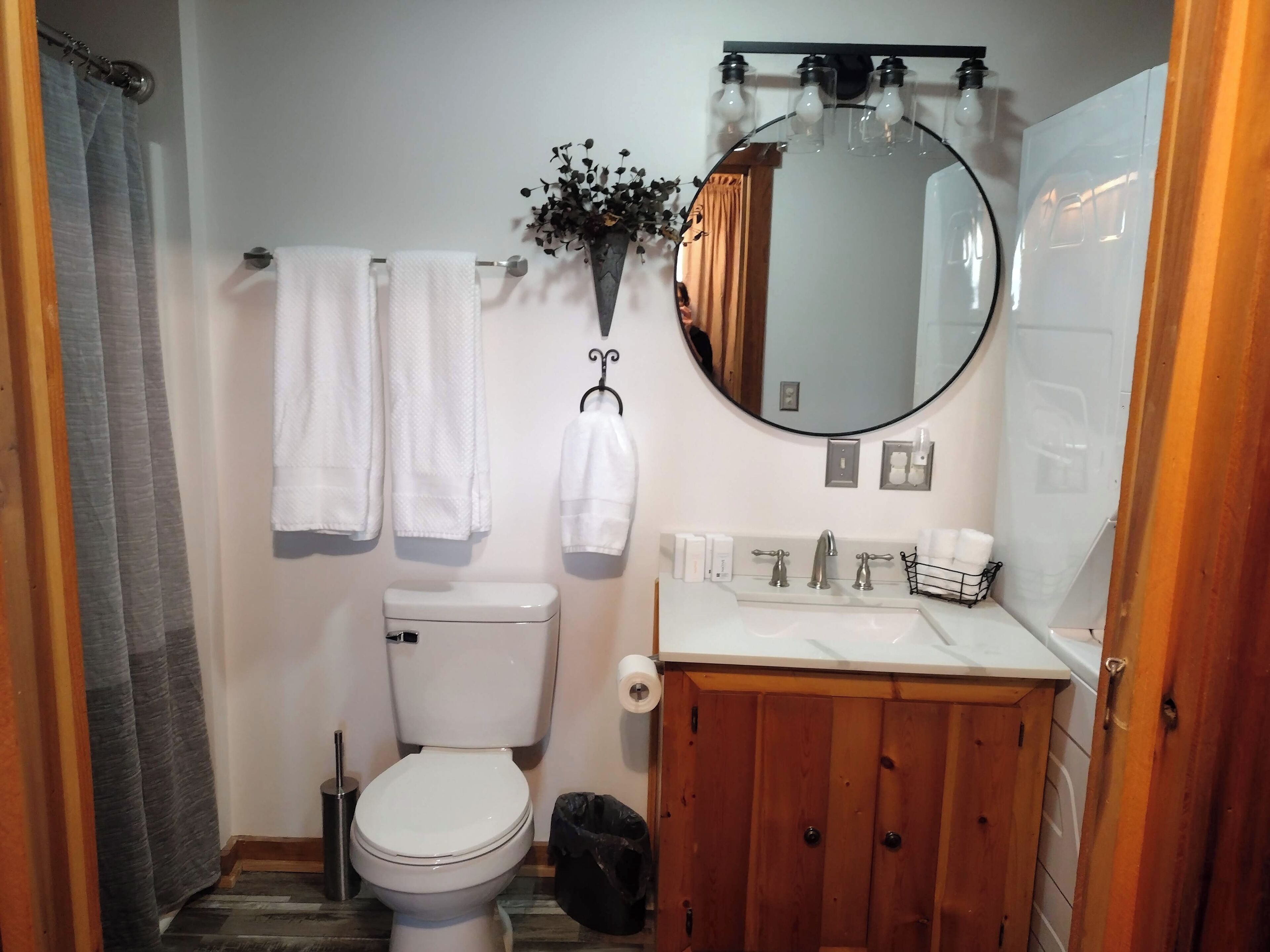 A bathroom with a toilet, sink, mirror, and towels.