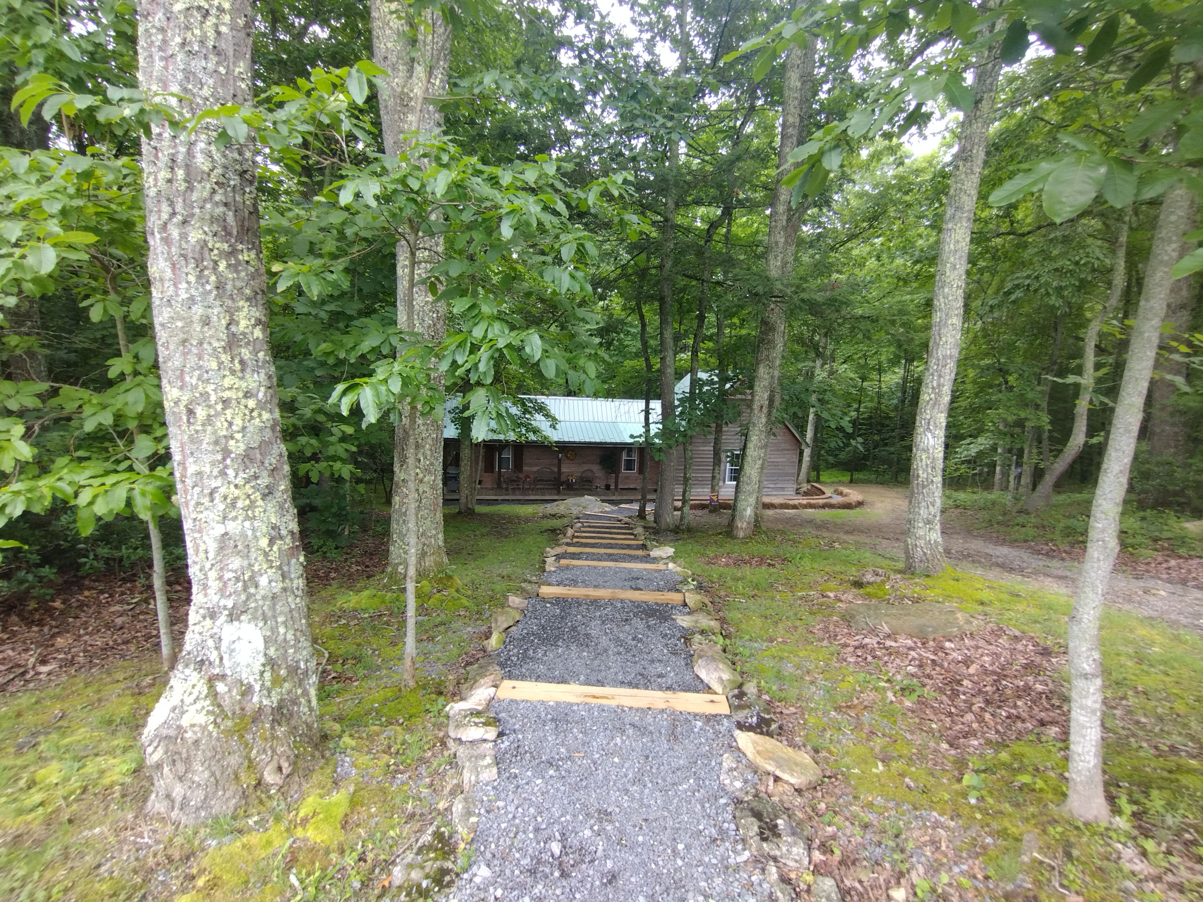 Eine Holzhütte mit Kiesweg, umgeben von Bäumen.
