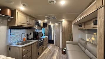 Cocina compacta para vehículos recreativos, con fregadero, estufa, microondas y refrigerador.