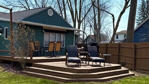 Een huis met een overdekte patio, tuinmeubilair en een houten omheining.
