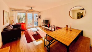 Uma sala de estar moderna com sofá, televisão, mesa de jantar e varanda com portas de correr.