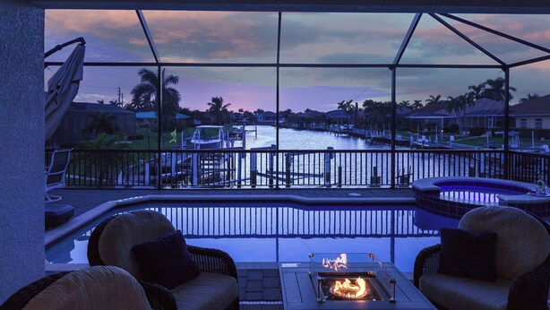 A pool area with a fire pit, lounge chairs, and a view of a marina. - Sunset Retreat Pool/Spa, great views, we love dogs (Punta Gorda)