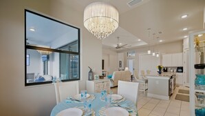 A dining area with a round table set for four, a chandelier, and a view through a large window. - Sunset Retreat Pool/Spa, great views, we love dogs (Punta Gorda)
