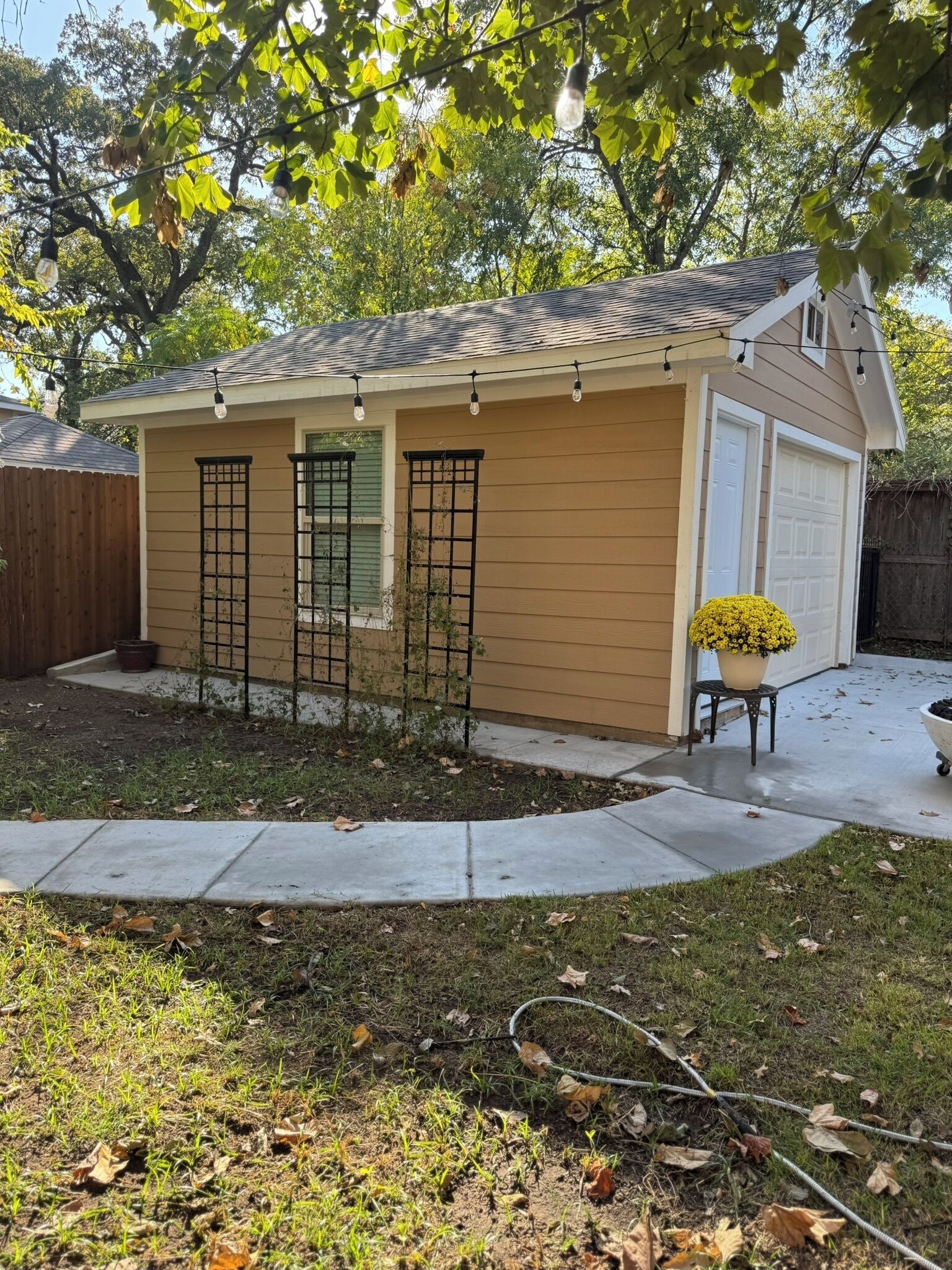 A single-story house with a garage, a small porch, and a garden area with a potted plant.