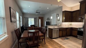 Una cocina amplia con armarios de madera, una isla central y una zona de comedor con una mesa grande y sillas.