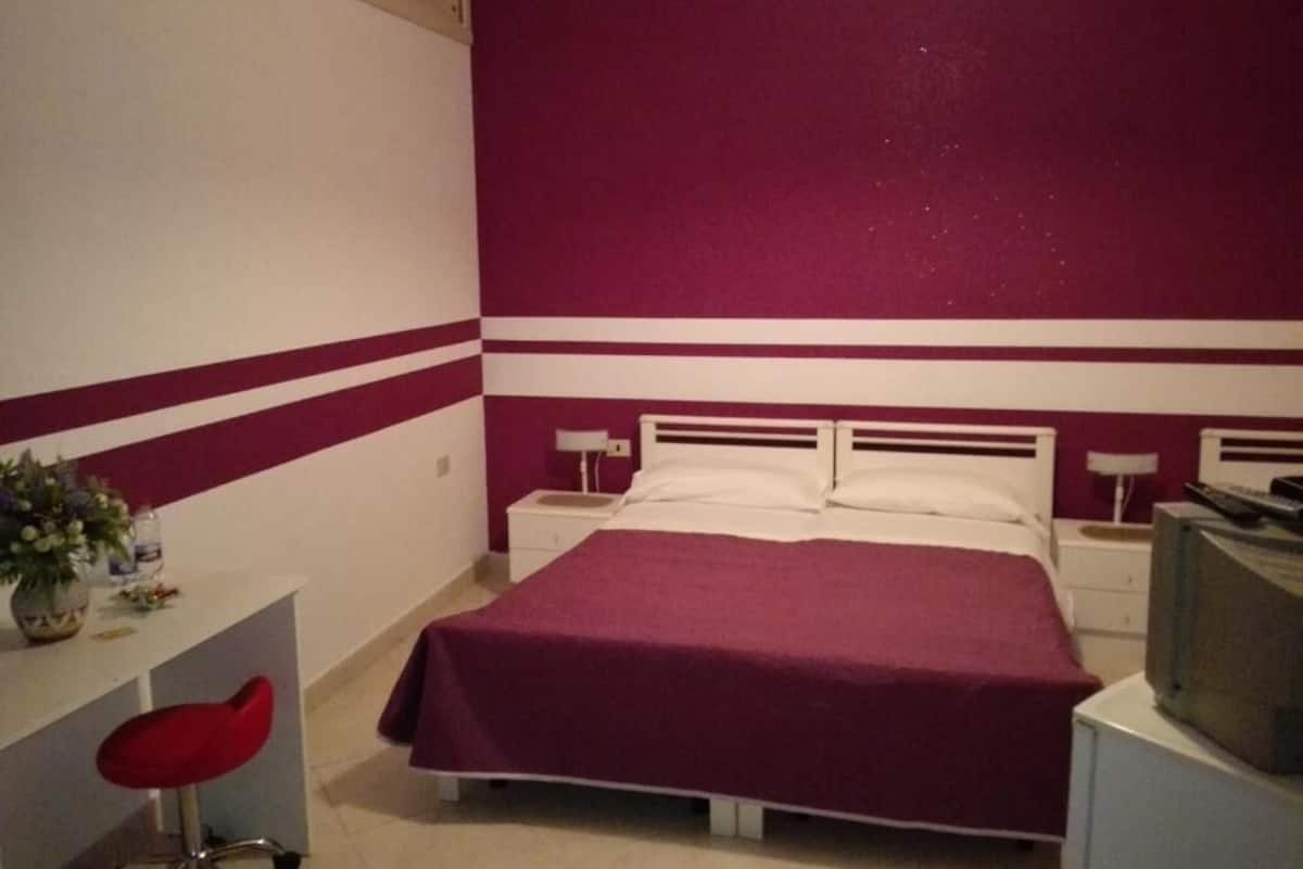Ein Schlafzimmer mit Bett, Nachttischen, einem Fernseher und einem Schreibtisch mit Stuhl.