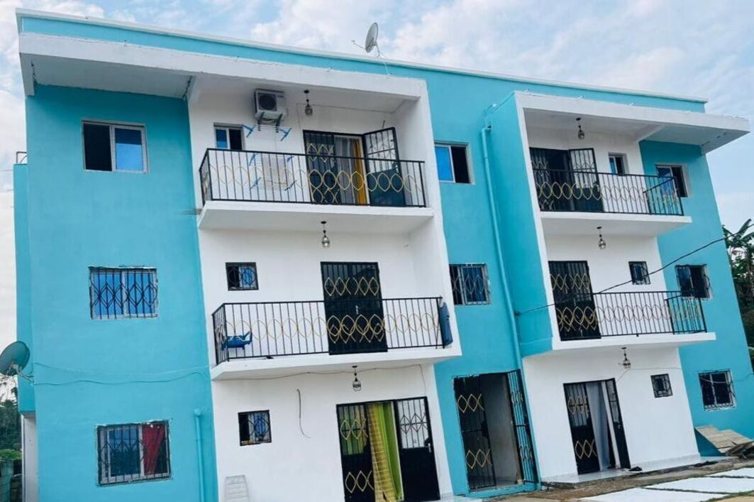 A multi-story residential building with balconies, satellite dishes, and a flat roof.