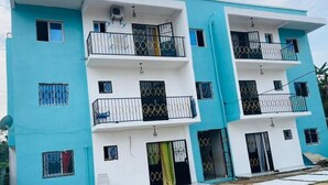 A multi-story residential building with balconies, satellite dishes, and a flat roof. - MyFurnishedYassa_Yatchika (Douala)