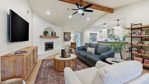 A modern living room with a flat-screen TV, a wooden coffee table, a gray sofa, and a bookshelf.
