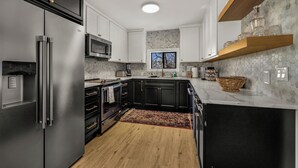 A modern kitchen with black cabinets, stainless steel appliances, and a wooden floor. - Farm barn with territorial view in Banks w/ pheasants- 1 hour drive to coastal (Banks)