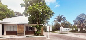 A modern building with a white facade, large windows, and a covered porch. - Canal-Front Villa in a Tropical Paradise in Leeward Settlement! (Leeward Settlement)
