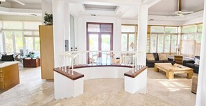 A spacious living area with a curved staircase, a dining table, and a sofa. - Canal-Front Villa in a Tropical Paradise in Leeward Settlement! (Leeward Settlement)
