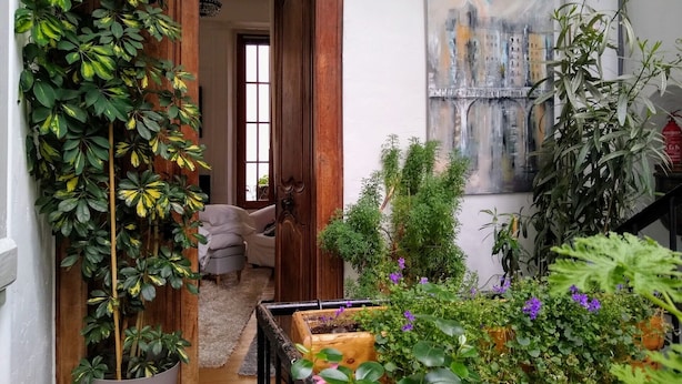 A cozy room with a wooden door, a sofa, and a painting of a cityscape. - Charming 26m2 studio in the center, 50m from the thermal baths (Bagnères-de-Bigorre)