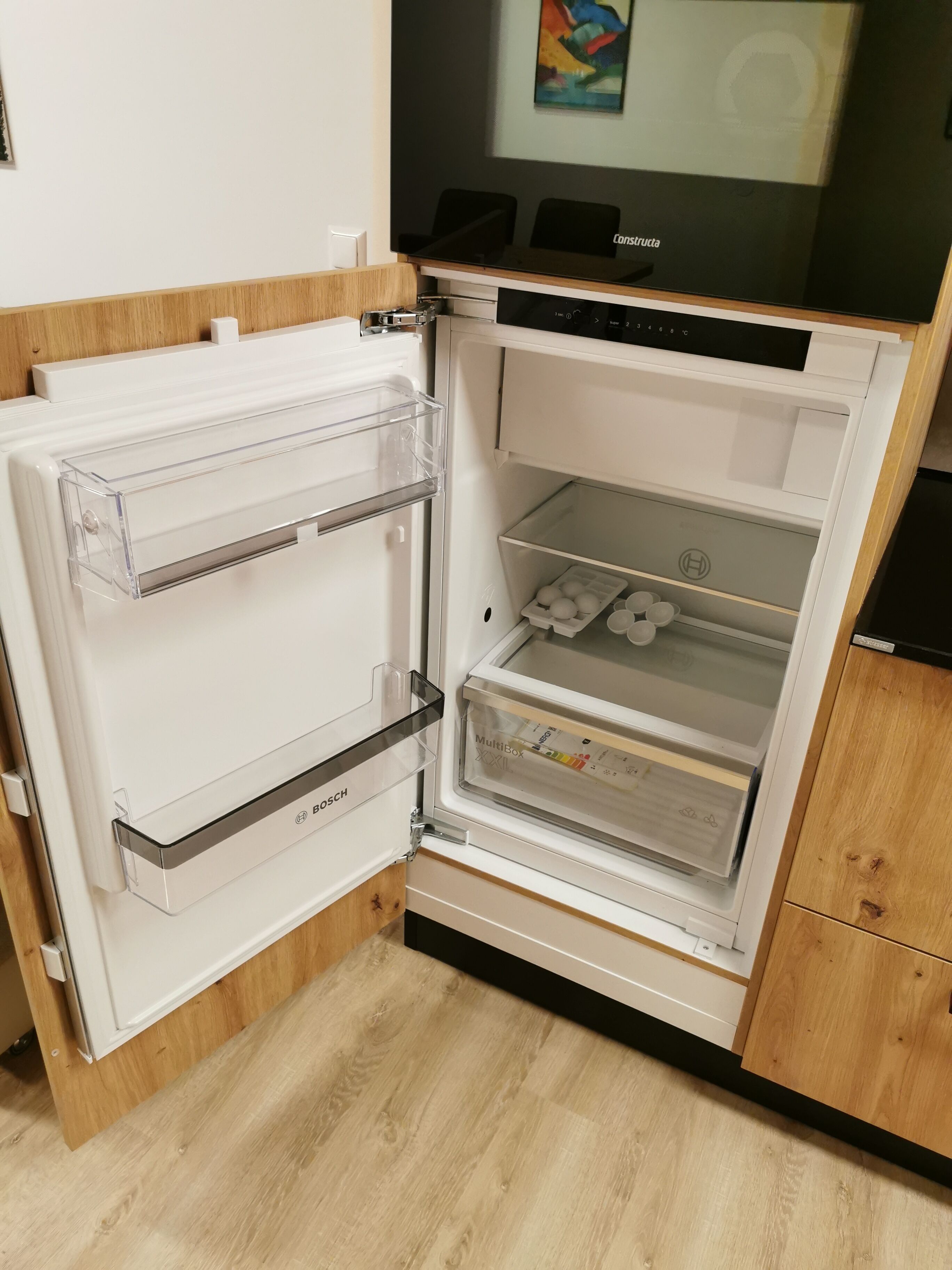 Ein offener Kühlschrank mit Mehrfachaufteilung, einschließlich eines Gefrierfachs und eines Hauptfachs mit Wasserspender.