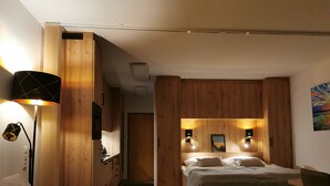 Et moderne soveværelse med sengegavl i træ, seng med grønt sengetæppe, et natbord og en lampe.