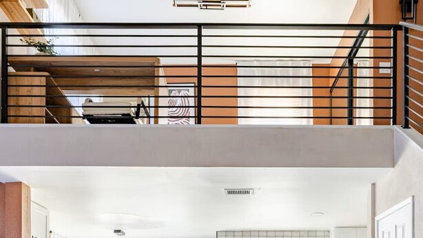 Um apartamento moderno estilo loft, com área de estar, cozinha e escada que leva a um andar superior.