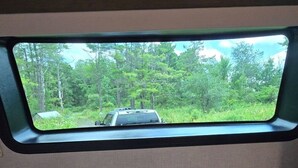 Un veicolo parcheggiato in una zona boschiva, visto attraverso un finestrino.
