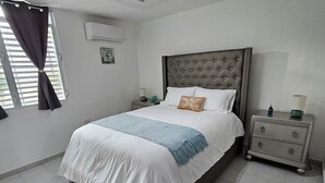 Ein Schlafzimmer mit einem großen Bett, einem Nachttisch, einem Teppich und einer Deckenleuchte.