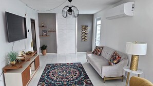 Ein modernes Wohnzimmer mit einer Couch, Sesseln, einem Fernseher und Dekorationselementen.