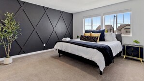 Quarto moderno com cama, parede de destaque escura, janela e uma pequena planta.