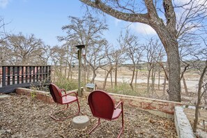 A patio with two red chairs, a small table, and a lamp post. - Guadalupe Getaway | Riverfront | Close to Town (Kerrville)