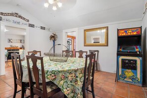 A dining area with a table set for four, surrounded by wooden chairs, a metal basket, and a wall-mounted mirror. - Guadalupe Getaway | Riverfront | Close to Town (Kerrville)