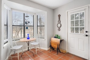 A corner room with a dining table, chairs, a small side table, and a door with a window. - Guadalupe Getaway | Riverfront | Close to Town (Kerrville)