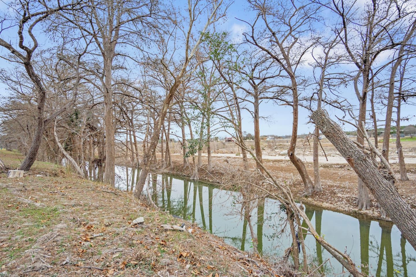 Un paysage naturel comprenant une étendue d’eau, des arbres et un ciel dégagé.