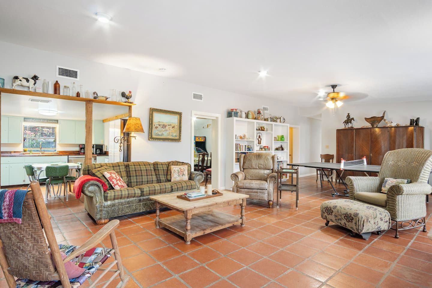 A spacious living room with a sofa, armchairs, a coffee table, and a dining table.