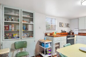 A kitchen with a window, cabinets, and a dining area with chairs. - Guadalupe Getaway | Riverfront | Close to Town (Kerrville)