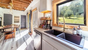A modern kitchen with a wooden ceiling, a large window, and a coffee sign. - Renovated Barn w/ Jacuzzi - Tree Table - 3 Acres (Ruckersville)