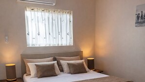 Une chambre à coucher avec un grand lit, une fenêtre avec des rideaux, un climatiseur et deux lampes de chevet.